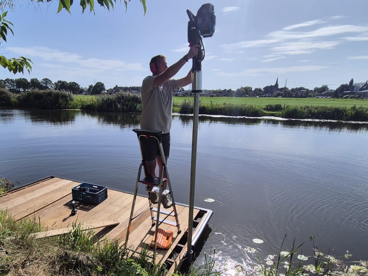 Verankering met buispalen in de grond en palenrammer Verankering met buispalen in de grond en palenrammer